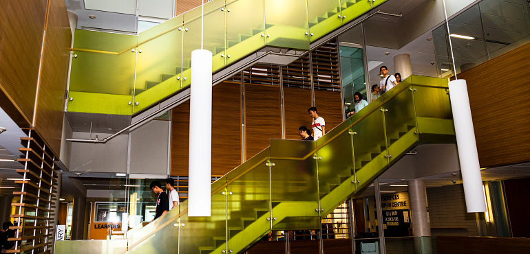 Students walking down the steps from the third floor to the second floor of the library and Learning Centre.